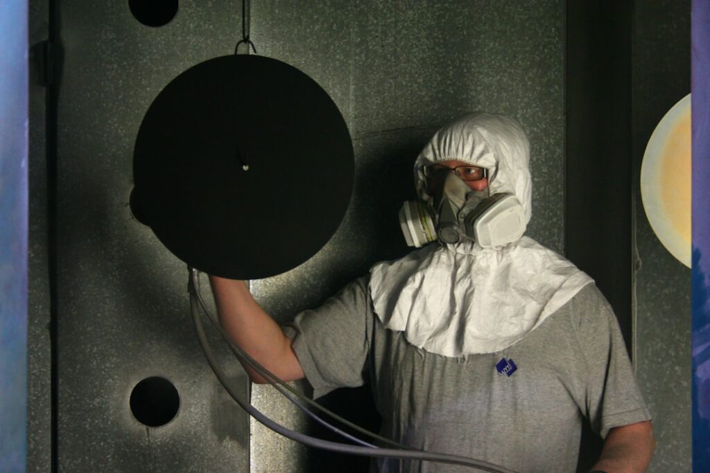 Spray gun applying an even sublimation coating in an industrial spray booth